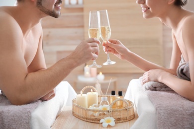 Romantic young couple with champagne in spa salon, closeup