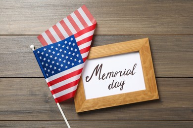 Photo of Frame with phrase Memorial Day and American flag on wooden table, flat lay