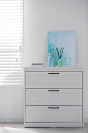 Photo of White chest of drawers near window in stylish room interior