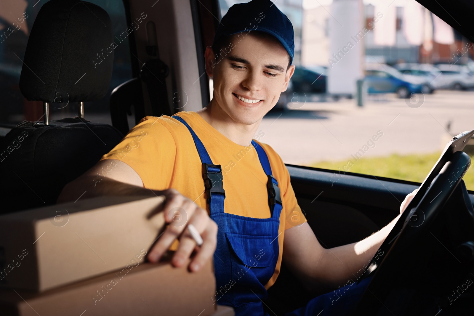 Photo of Courier with clipboard checking packages in car