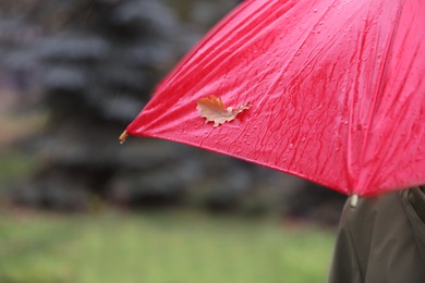 Person holding wet umbrella with autumn leaf outdoors, closeup view