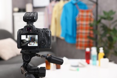 Photo of Beauty blogger's workplace. Cosmetic products and clothes indoors, focus on camera