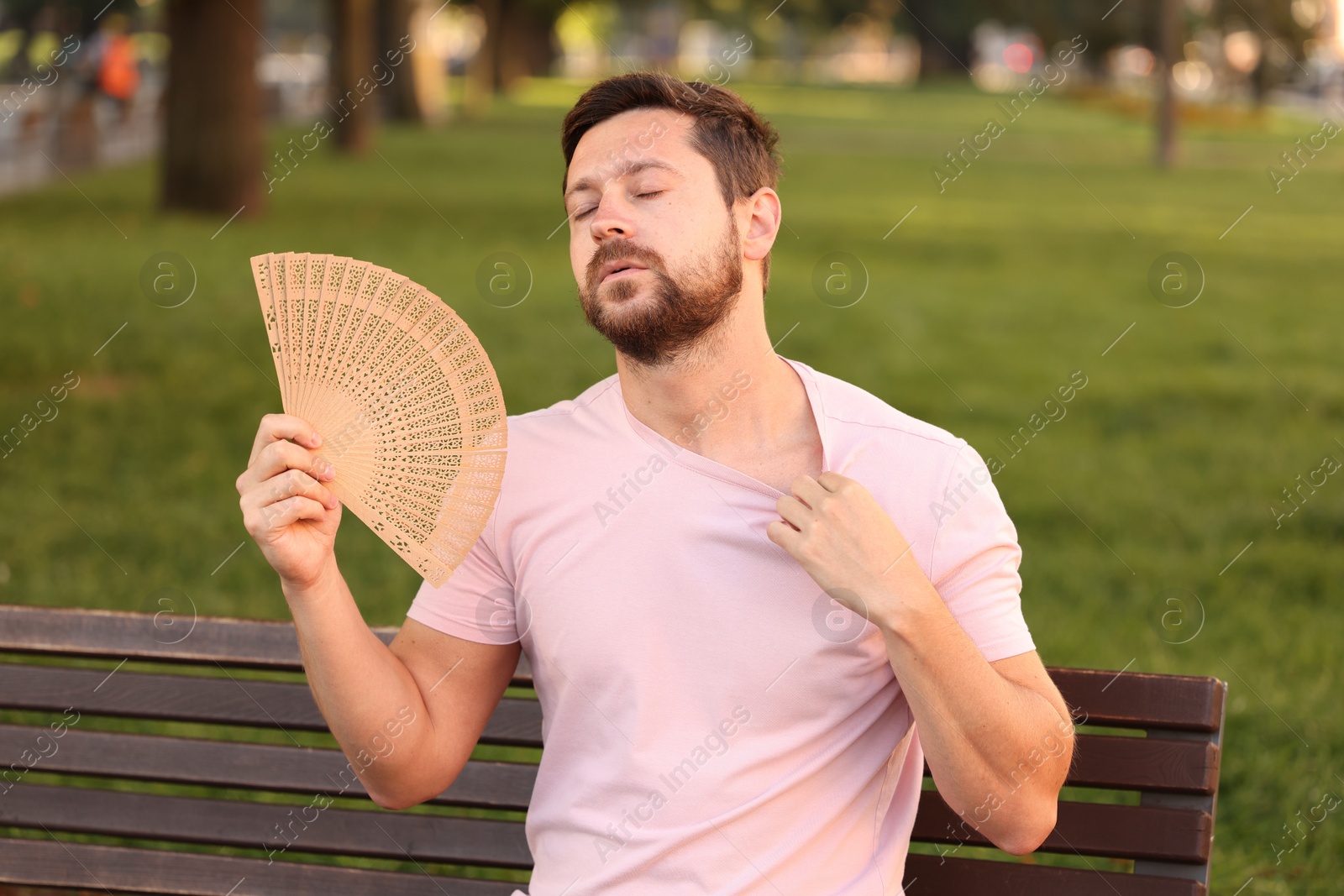 Photo of Man with hand fan suffering from heat outdoors