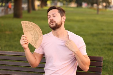 Man with hand fan suffering from heat outdoors