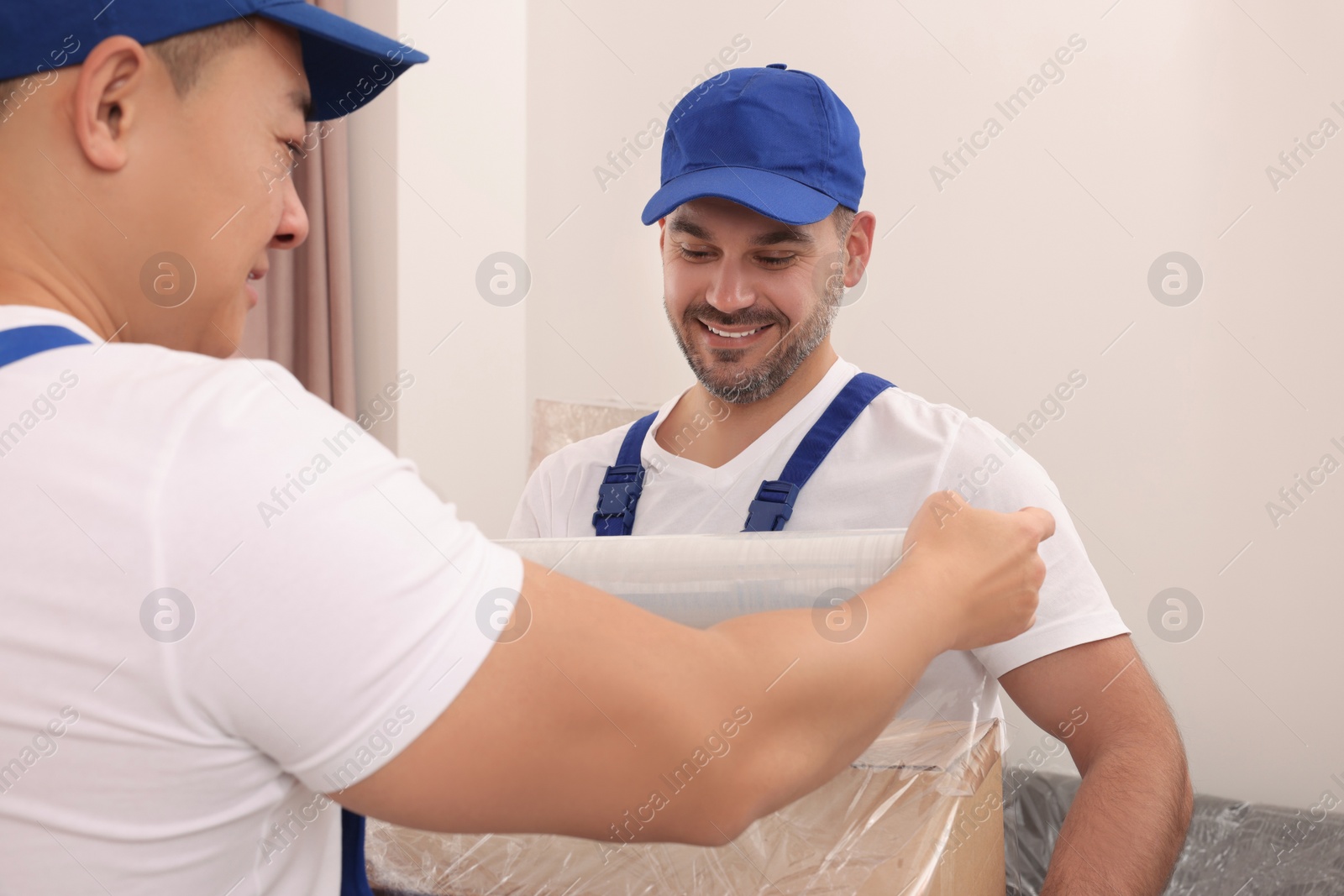 Photo of Workers wrapping box in stretch film indoors