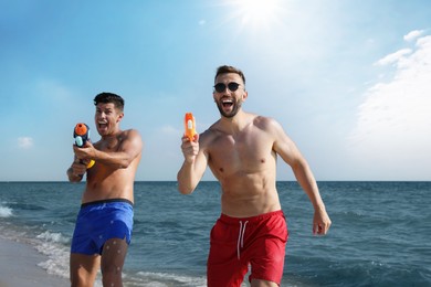 Friends with water guns having fun on beach