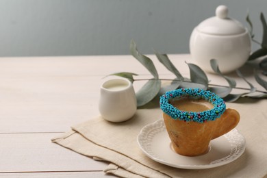 Photo of Delicious edible biscuit cup of espresso decorated with sprinkles on white wooden table, space for text