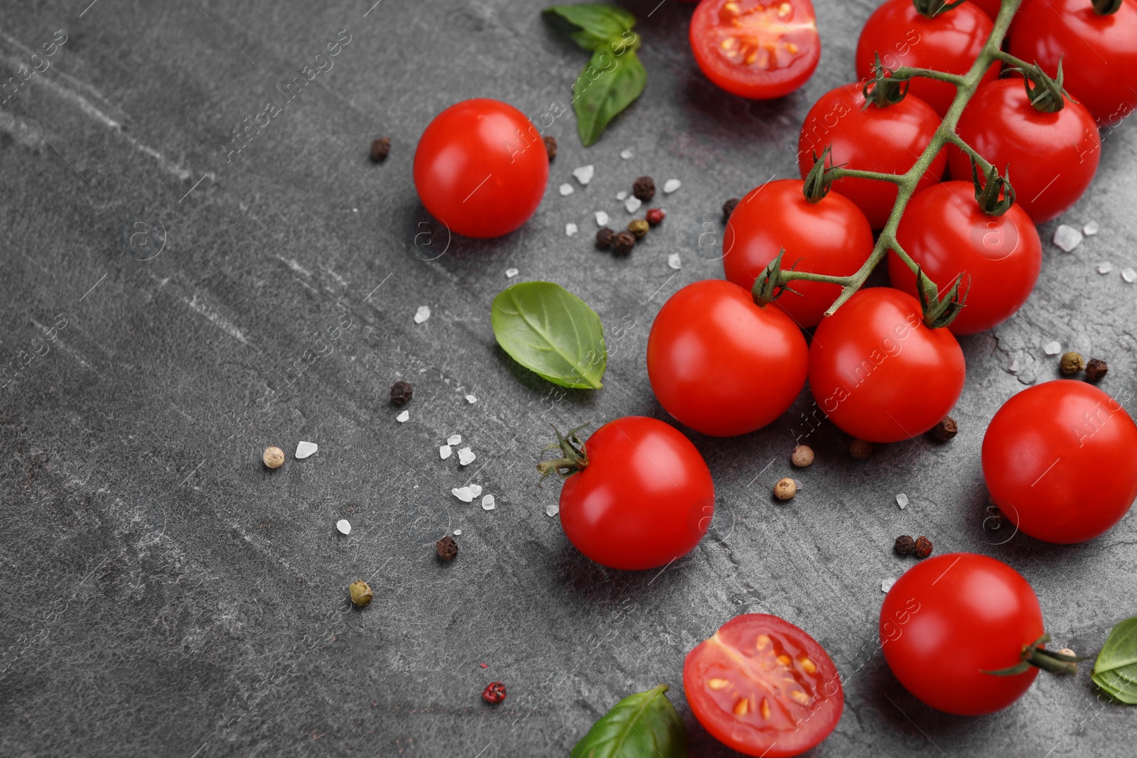 Photo of Ripe tomatoes, basil and spices on gray textured table, above view. Space for text