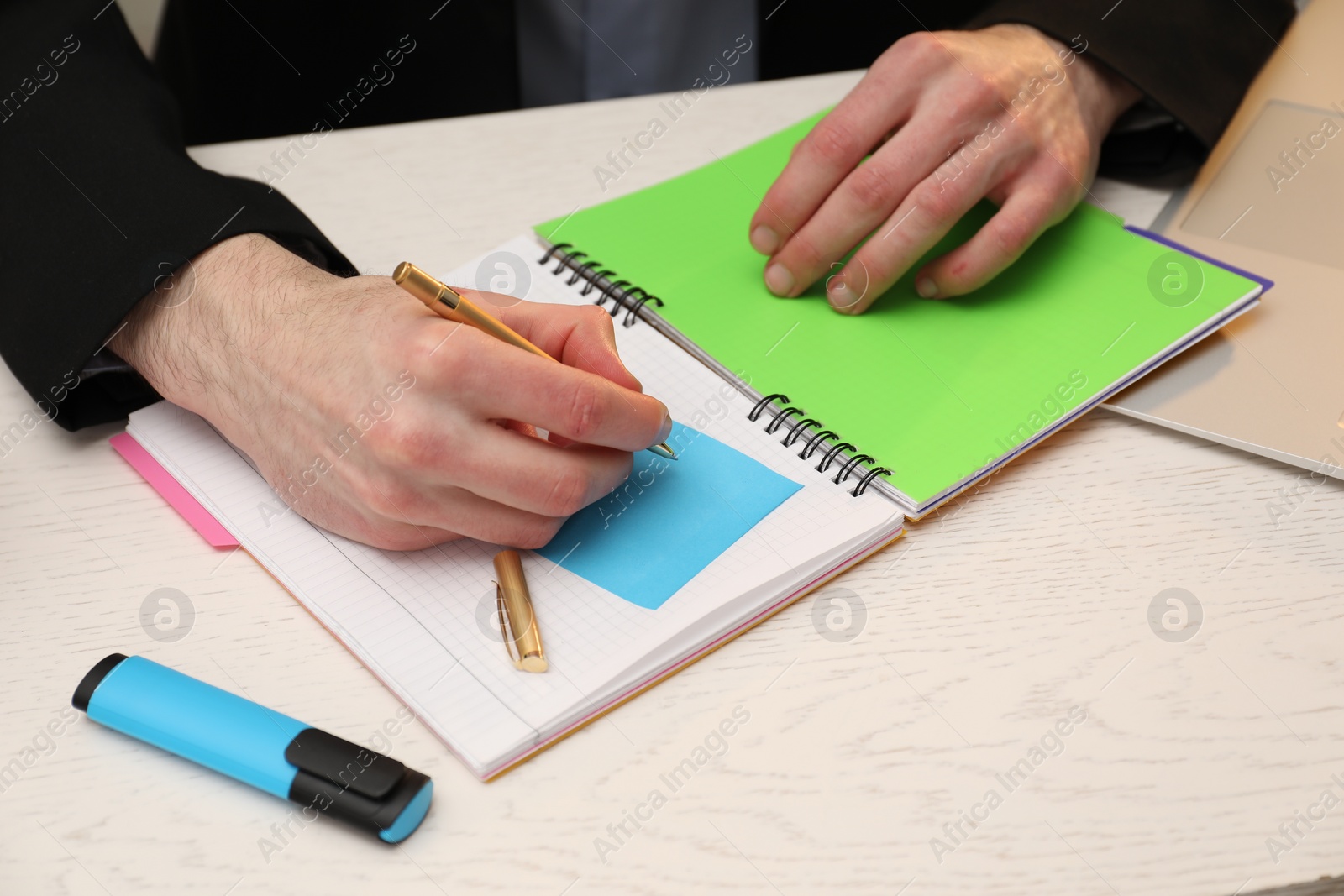 Photo of Man taking notes at white wooden table, closeup