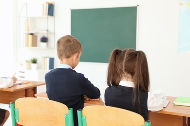 Photo of Little children in classroom. Stylish school uniform