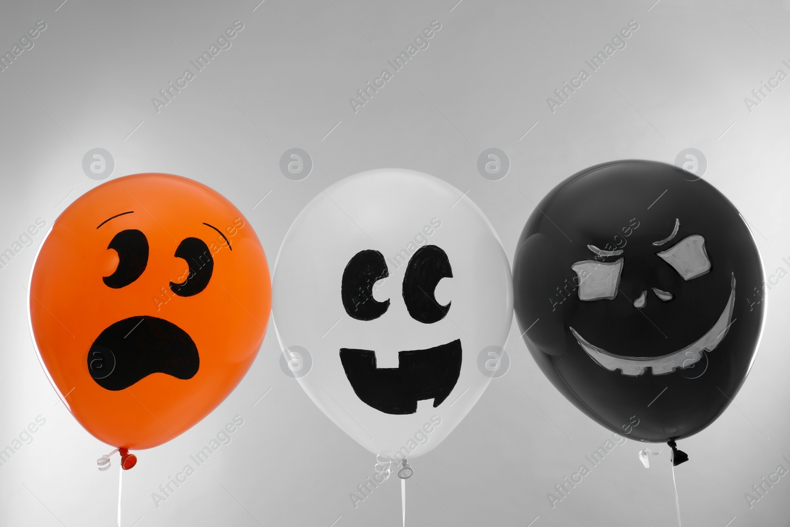 Photo of Spooky balloons for Halloween party on light grey background