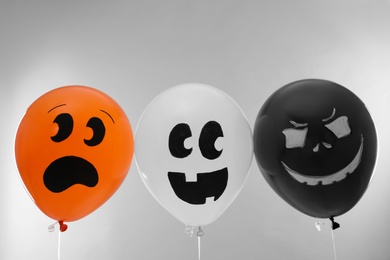 Photo of Spooky balloons for Halloween party on light grey background