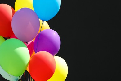 Photo of Bunch of colorful balloons on black background. Space for text