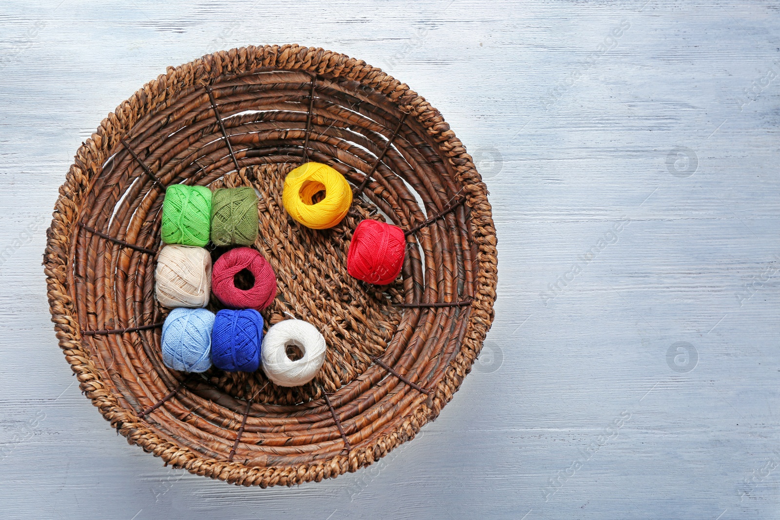 Photo of Basket with set of color sewing threads on wooden background