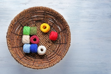 Photo of Basket with set of color sewing threads on wooden background