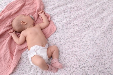 Photo of Little baby in diaper on bed, top view. Space for text