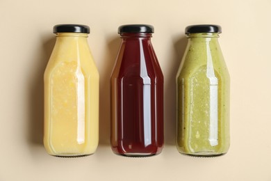 Photo of Bottles with delicious colorful juices on beige background, flat lay