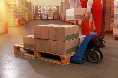Image of Worker taking cardboard box from pallet in warehouse, closeup