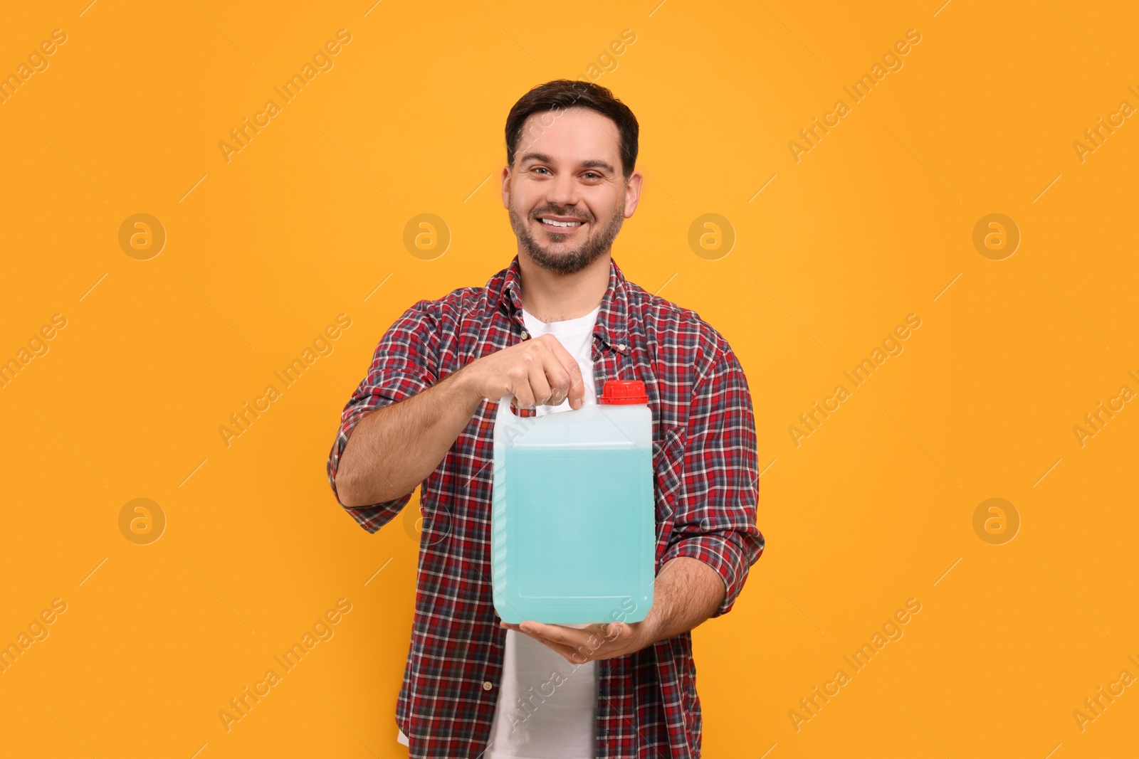 Photo of Man holding canister with blue liquid on orange background