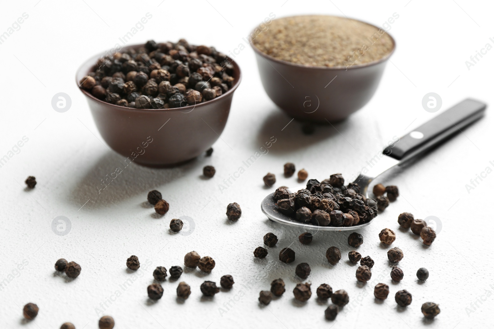 Photo of Ground black pepper and corns on light table