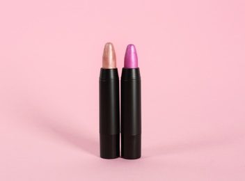 Bright lipsticks in black tubes on pink background