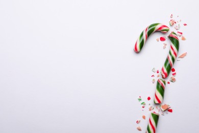 Photo of Broken sweet Christmas candy cane on white background, top view. Space for text