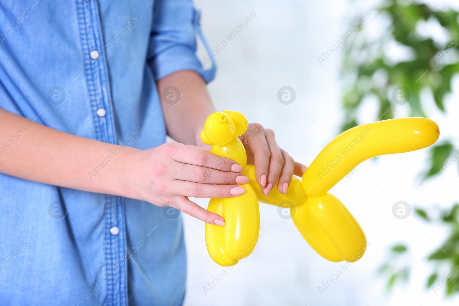 Photo of Woman making balloon figure on blurred background, closeup