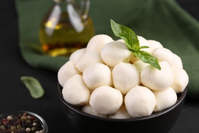 Photo of Tasty mozzarella balls and basil leaves in bowl, closeup. Space for text
