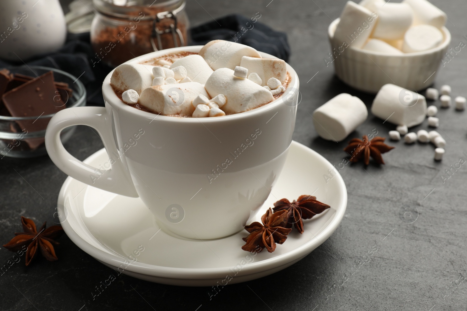 Photo of Tasty hot chocolate with marshmallows on dark textured table, closeup