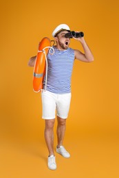 Emotional sailor with binoculars and ring buoy on yellow background
