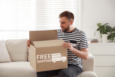 Image of Happy young man opening parcel at home. Free shipping