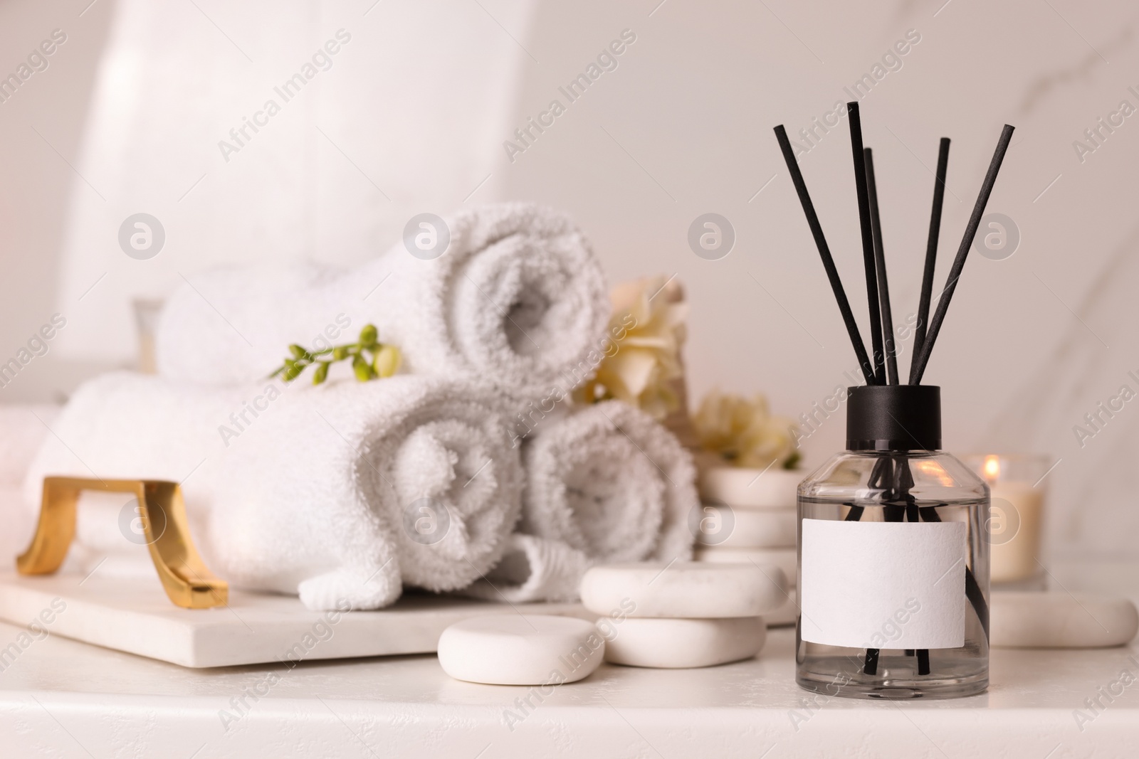 Photo of Aromatic reed air freshener and spa stones on white table, space for text