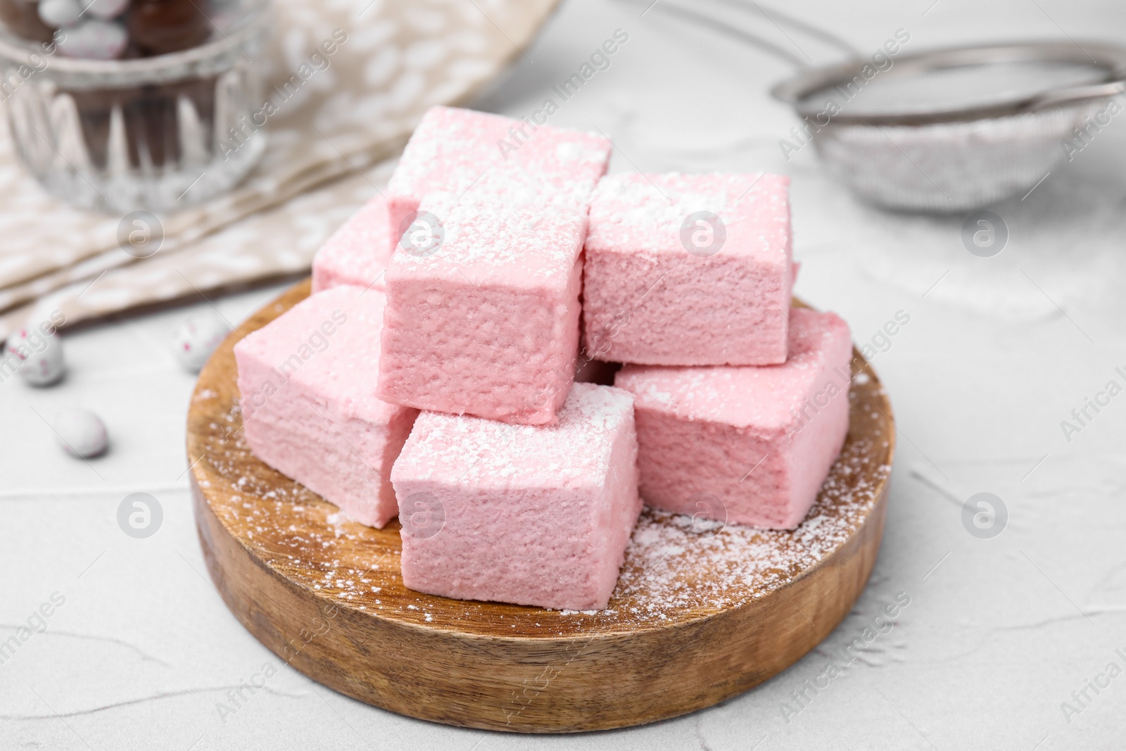 Photo of Tasty marshmallows with powder sugar on white textured table, closeup