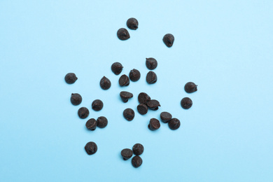 Photo of Delicious dark chocolate chips on light blue background, top view