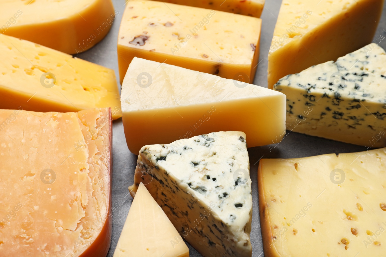 Photo of Different kinds of delicious cheese on stone background, closeup