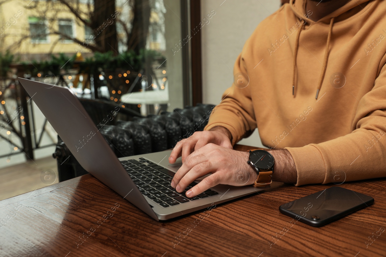 Photo of Male blogger working with laptop at table in cafe, closeup