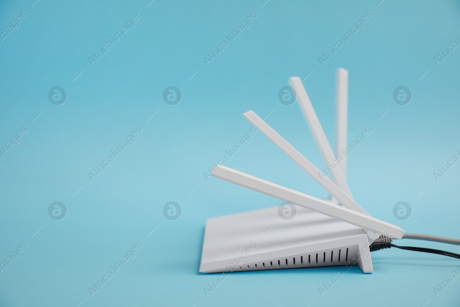 Photo of Modern Wi-Fi router on light blue background. Space for text