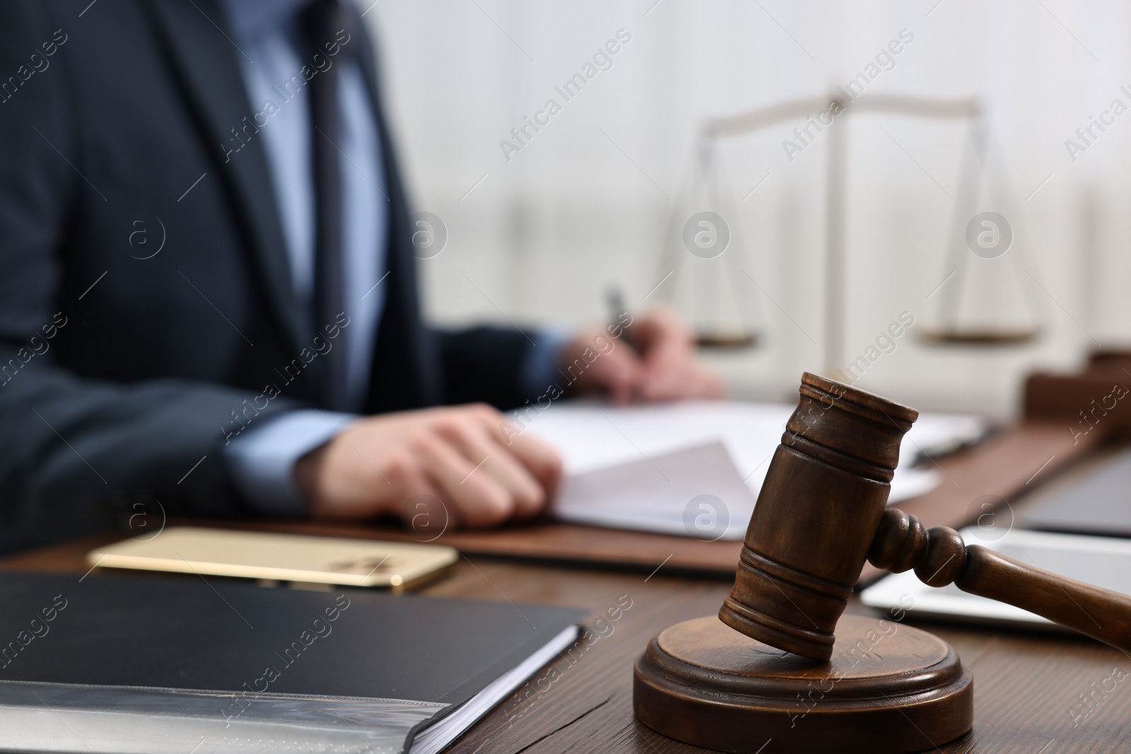 Photo of Lawyer working with documents at wooden table, focus on gavel