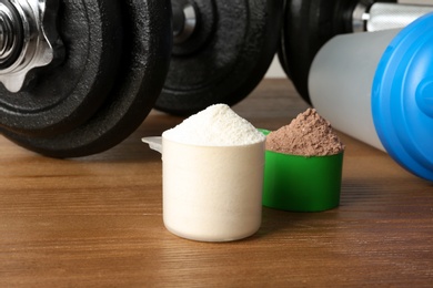 Photo of Scoops with protein shake powders on table, closeup