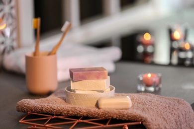 Photo of Soap bars and towel on table against blurred background. Space for text