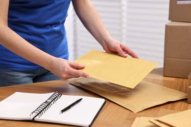 Post office worker packing parcel at wooden table indoors, closeup