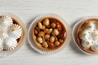 Photo of Different tartlets on white wooden table, flat lay. Tasty dessert