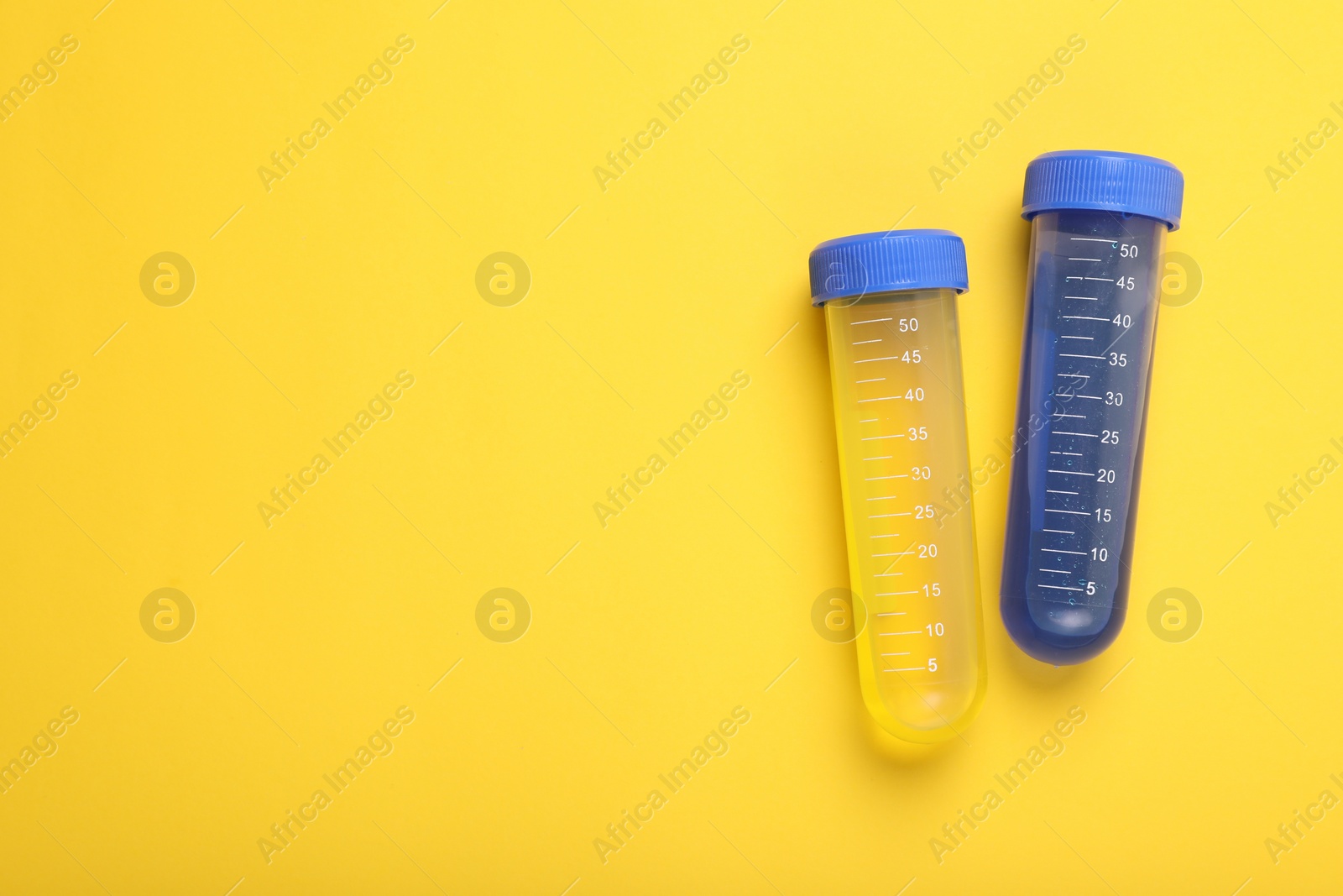 Photo of Test tubes with colorful liquids on yellow background, flat lay and space for text. Kids chemical experiment set