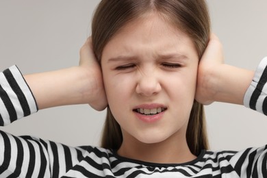 Photo of Hearing problem. Little girl suffering from ear pain on grey background