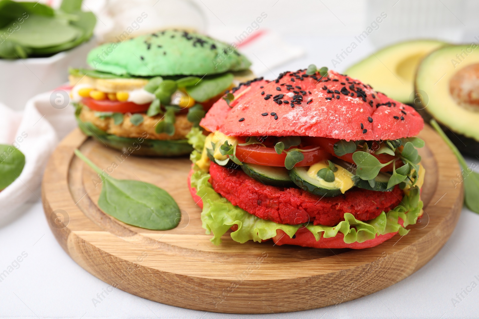 Photo of Tasty pink vegan burger with vegetables, patty and microgreens on white table, closeup. Space for text