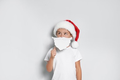 Cute little boy with Santa hat and white beard prop on white background. Christmas celebration