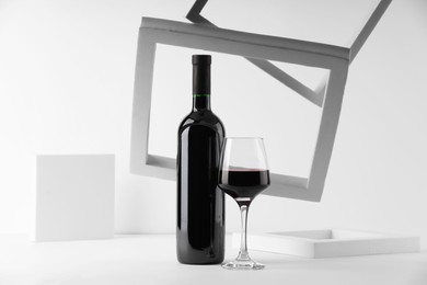 Stylish presentation of delicious red wine in bottle and glass on white background