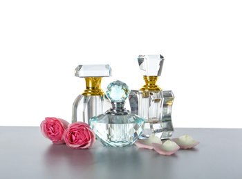 Photo of Bottles with perfumes and flowers on grey table