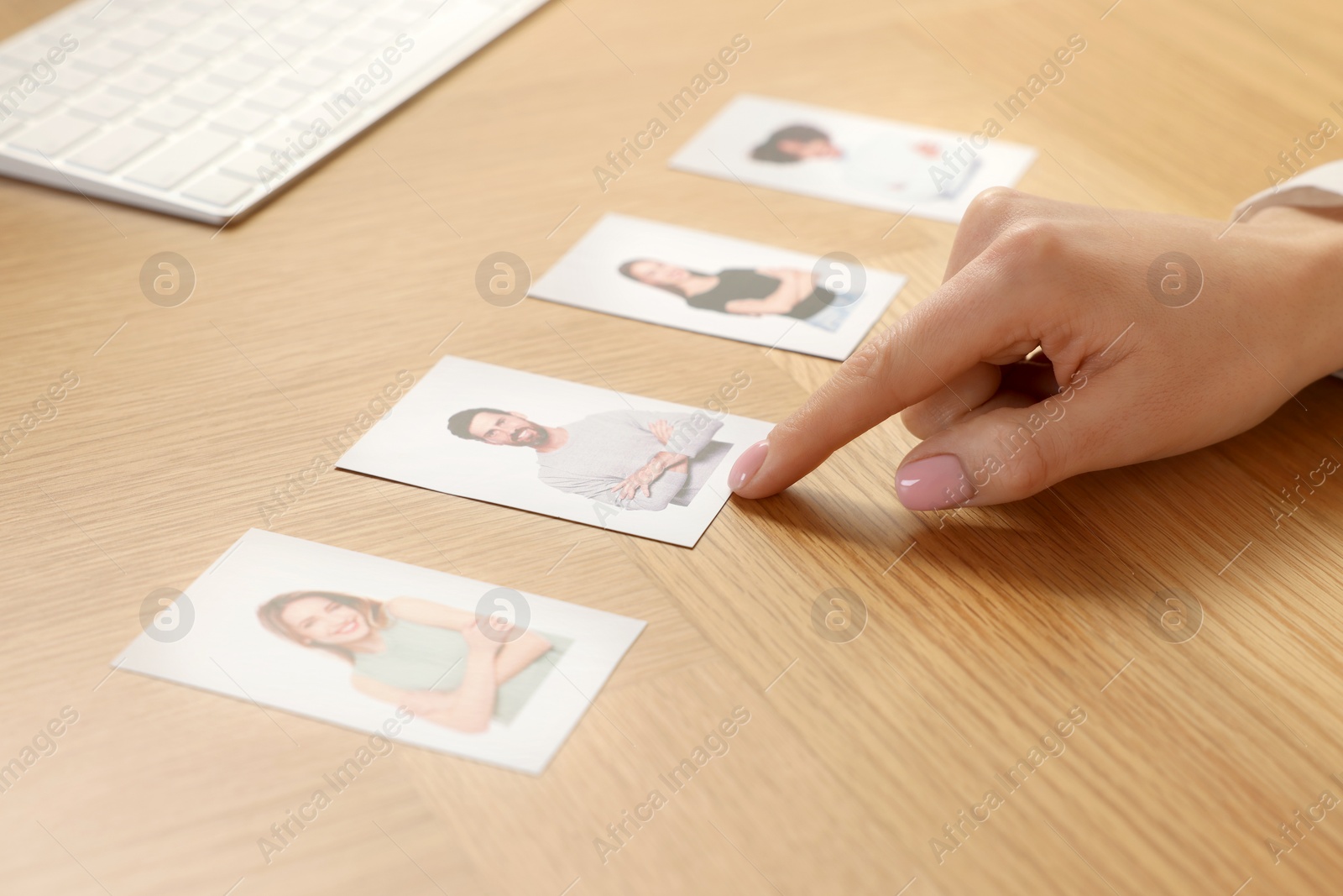 Photo of Human resources manager choosing employee among different applicants at wooden table, closeup