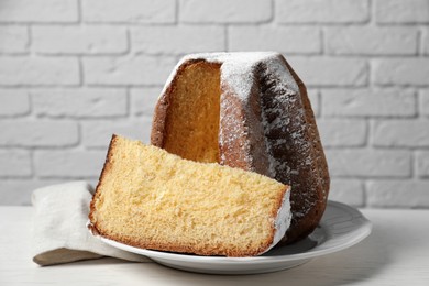 Photo of Delicious Pandoro cake decorated with powdered sugar on white table. Traditional Italian pastry